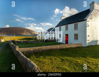 Maison de ferme blanche avec porte rouge à côté de la plage sur l'île d'Achill sur la voie de l'Atlantique sauvage dans le comté de Mayo en Irlande Banque D'Images
