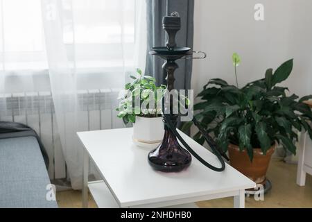 Bol à narguilé de shisha avec des charbons chauds rouges et du tabac artisanal. Un narguilé moderne avec du charbon de coco pour se détendre et fumer dans le salon. Banque D'Images