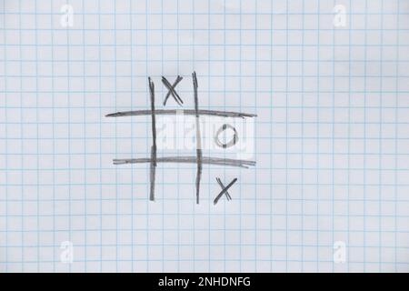 le jeu de tic-tac-toe est dessiné avec un crayon sur un carnet d'école dans une cage comme arrière-plan, Banque D'Images