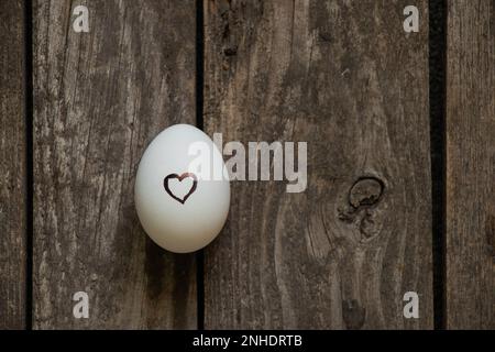 cœur tiré sur un œuf de poulet blanc sur une table en bois Banque D'Images