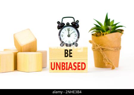 Être un symbole impartial. Les mots-concepts doivent être impartiaux sur un bloc de bois. Magnifique table blanche fond blanc. Radio-réveil noir. Plante de maison verte. Entreprise Banque D'Images