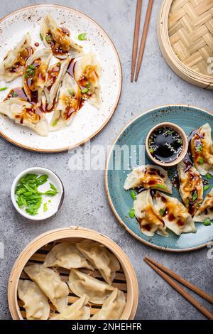 Vue rapprochée de deux assiettes avec boulettes asiatiques traditionnelles, sauce soja et baguettes sur fond gris rustique en pierre. Chinois authentique Banque D'Images