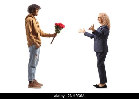 Jeune africain américain donnant des roses rouges à une femme mûre surprise isolée sur fond blanc Banque D'Images