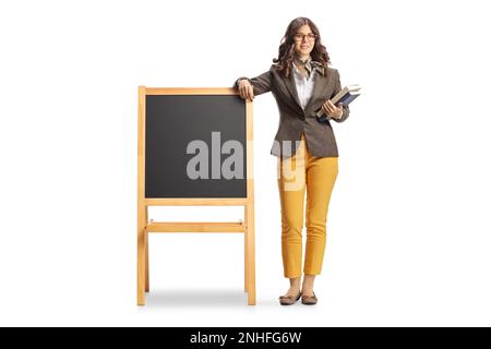 Portrait complet d'une jeune enseignante penchée sur un tableau noir vierge isolé sur fond blanc Banque D'Images