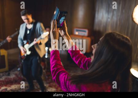 Belle femme chanteuse prenant des photos pendant la répétition de groupe. Photo de haute qualité Banque D'Images