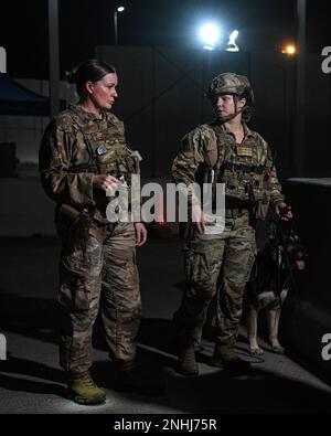 (À partir de la gauche) Tech. Le Sgt Michelle Beltran, contrôleur d'entrée affecté à l'escadron 380th des forces expéditionnaires de sécurité, informe le Sgt McKenzie Langan, un maître-chien militaire affecté à l'ESFS 380th, de l'activité d'un conducteur non identifié lors d'un exercice d'entraînement 29 juillet 2022, à la base aérienne Al Dhafra, Émirats arabes Unis. En tant que manutentionnaire, Langan et son MWD, Ajda, ont été appelés à rechercher un véhicule suspect. Banque D'Images