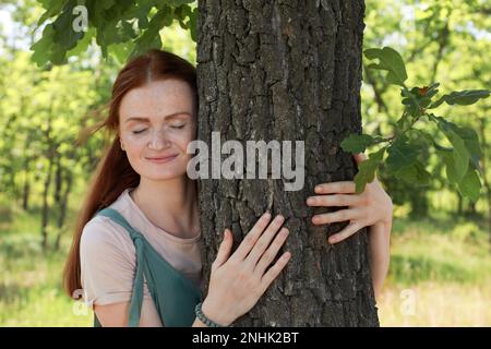 Belle femme embrassant le tronc d'arbre dans la forêt Banque D'Images