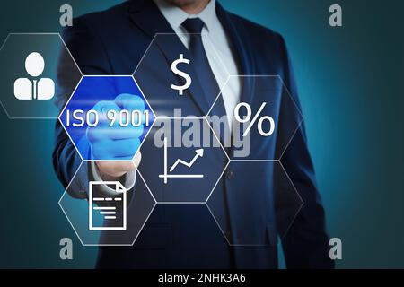 Homme d'affaires pointant sur l'icône virtuelle avec le texte ISO 9001 sur fond de couleur, gros plan Banque D'Images