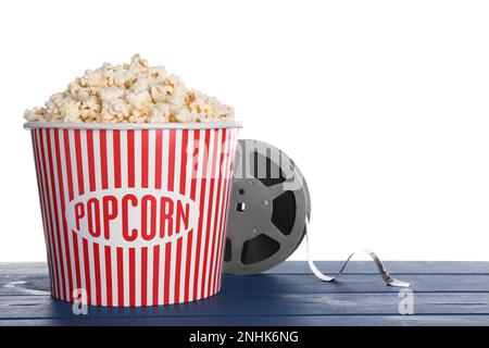 Délicieux pop-corn et rouleau de film sur table en bois bleu sur fond blanc Banque D'Images