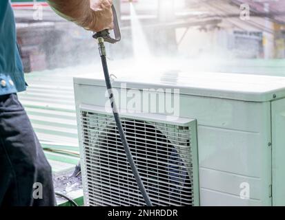 Nettoyage du climatiseur par un homme. Le technicien nettoie l'unité de condensation du climatiseur en pulvérisant de l'eau. Entretien du climatiseur à domicile Banque D'Images