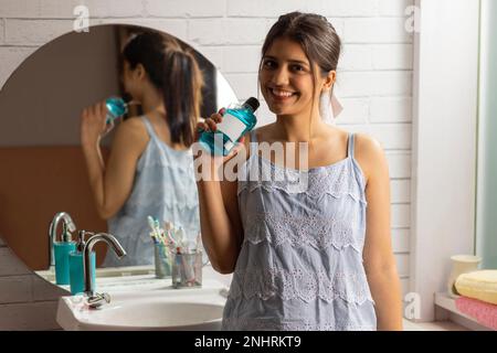 Femme souriante tenant une bouteille de bain de bouche Banque D'Images