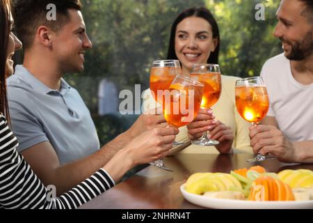Les amis se sont servis de verres de cocktails Aperol Spritz à table Banque D'Images