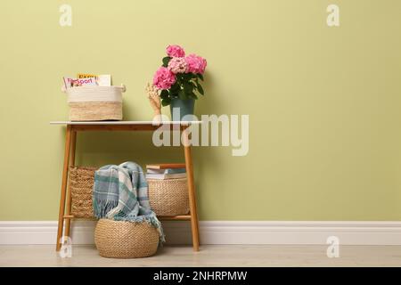 Table de console avec décor et belle fleur de hortensia près du mur vert clair dans le couloir, espace pour le texte. Design intérieur Banque D'Images