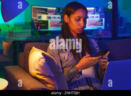Téléphone, dactylographie et triste femme à la maison sur les médias sociaux, SMS ou navigation sur Internet dans la lumière du néon. Nuit, technologie et femme programmeur sur le canapé avec Banque D'Images