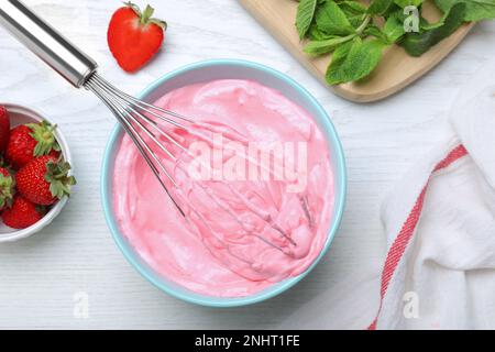 Crème fraise avec fouet ballon sur table en bois blanc, plat Banque D'Images