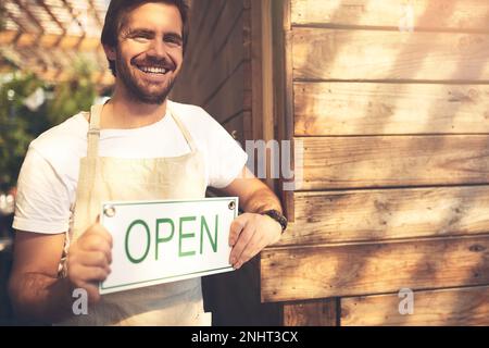 Un bon service vous attend. un propriétaire d'entreprise méconnaissable tenant un panneau dans la porte de son café. Banque D'Images