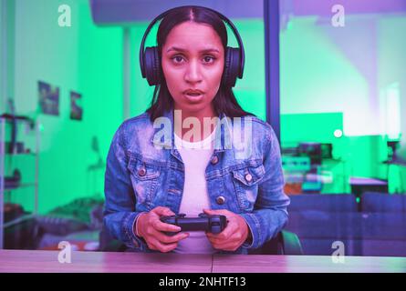 Joueur, casque et portrait de femme à la maison la nuit dans la lumière de néon pour Web esports. Face de jeu, cyber-technologie et gen z femelle avec contrôleur Banque D'Images