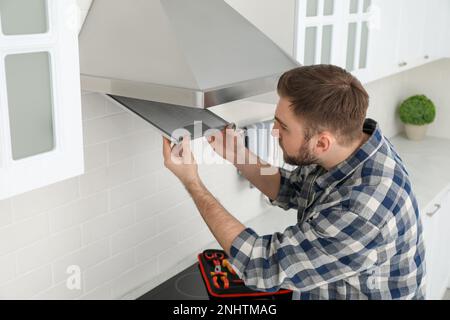 Homme répare une hotte moderne dans la cuisine Banque D'Images