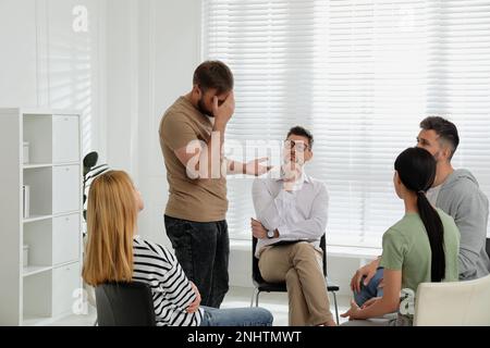 Psychothérapeute travaillant avec un groupe de personnes toxicomanes à la séance de thérapie à l'intérieur Banque D'Images