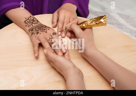 Maître de fabrication de tatouage au henné sur la main à la table en bois, gros plan. Mehndi traditionnel Banque D'Images