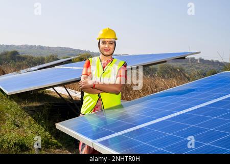 Portrait de la jeune femme indienne technicien portant un chapeau dur jaune debout près de panneaux solaires.travailleur industriel installation du système solaire, alternative Banque D'Images