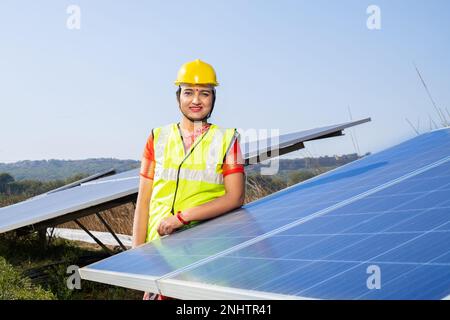 Portrait de la jeune femme indienne technicien portant un chapeau dur jaune debout près de panneaux solaires.travailleur industriel installation du système solaire, alternative Banque D'Images