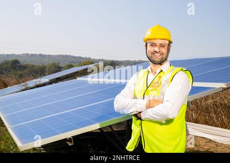 Portrait de jeune homme indien technicien portant un chapeau dur jaune debout près des panneaux solaires.travailleur industriel installation du système solaire, alternative RE Banque D'Images