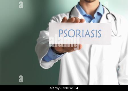 Médecin tenant signe avec le mot PSORIASIS sur fond de couleur, gros plan Banque D'Images