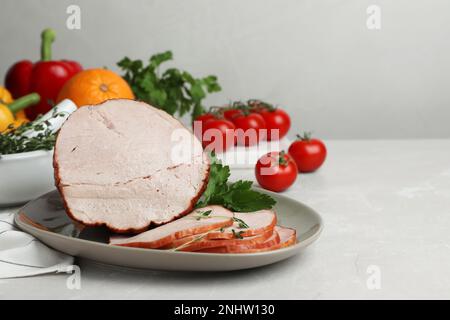 Délicieux jambon coupé servi avec du persil sur une table gris clair, espace pour le texte Banque D'Images