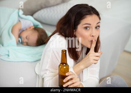 mère buvant de la bière demandant le silence Banque D'Images