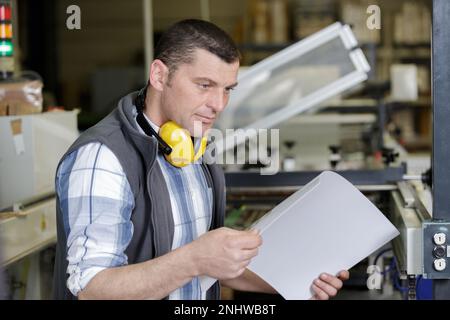 l'employé doit aligner une pile de papier dans la machine à découper Banque D'Images