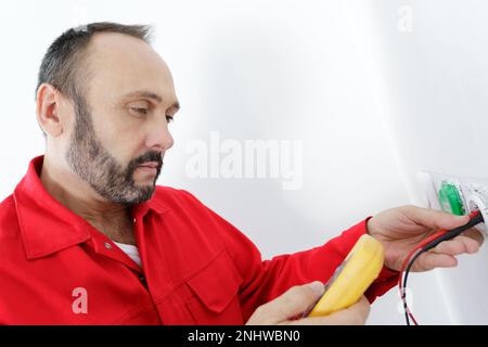 un électricien vérifie la tension d'une prise Banque D'Images