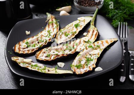 Sauce au yaourt et aubergines grillées sur fond noir. Aubergine cuite au four. Banque D'Images