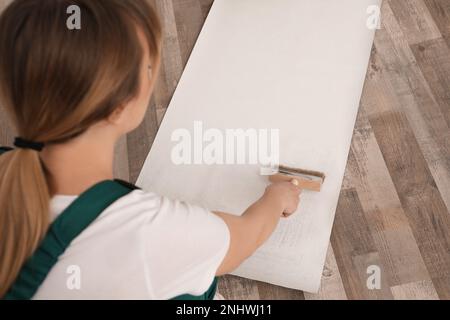 Employé appliquant de la colle sur la feuille de papier peint, se concentrer sur la main Banque D'Images