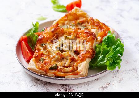 Mini pizza pour enfants, petites tartes ouvertes avec jambon, sauce tomate, mozzarella et fromage dans un panier sur fond clair. Banque D'Images