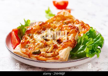 Mini pizza pour enfants, petites tartes ouvertes avec jambon, sauce tomate, mozzarella et fromage dans un panier sur fond clair. Banque D'Images