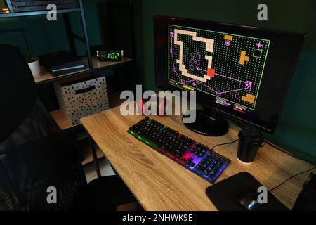 Ordinateur moderne, clavier RVB et écouteurs sur table en bois à l'intérieur Banque D'Images