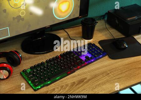 Clavier RVB moderne, ordinateur et casque sur table en bois à l'intérieur Banque D'Images