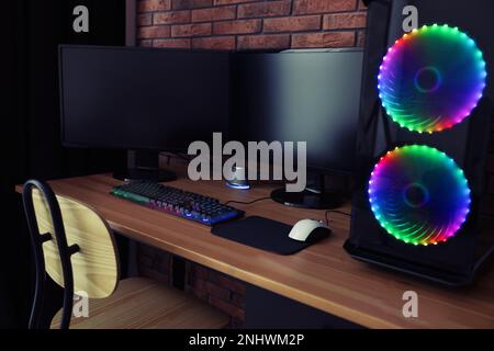 Ordinateur moderne et clavier RVB sur table en bois à l'intérieur Banque D'Images