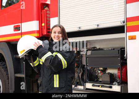 Portrait d'un pompier en uniforme avec un casque près d'un camion d'incendie Banque D'Images