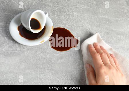 Femme essuyant du café renversé sur une table grise, gros plan Banque D'Images