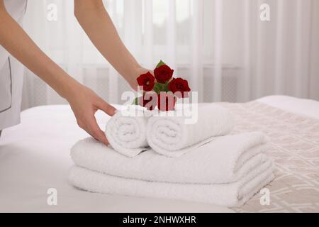 Femme de chambre en train de mettre des fleurs avec des serviettes fraîches dans la chambre d'hôtel, en gros plan Banque D'Images