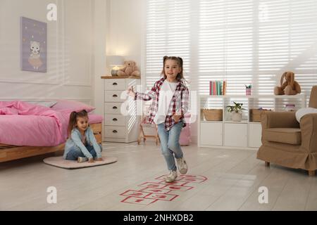 Mignons petites filles jouant le hopscotch à la maison Banque D'Images