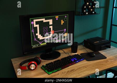 Ordinateur moderne, clavier RVB et écouteurs sur table en bois à l'intérieur Banque D'Images