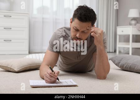 Homme résolvant le sudoku sur le sol à la maison Banque D'Images