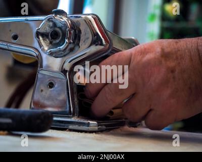 caucasien homme senior pâte roulante à main pour pâtes maison non cuites de machine italienne dans les mains avec la farine de semoule sur la texture de marbre blanc Banque D'Images