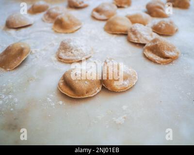 Gros plan sur la fabrication de tortelli farcis avec de la citrouille remplissant des pâtes maison, grand-mère cuisinier de saison 'tortelli di zucca', traditionnel italien rempli pas Banque D'Images