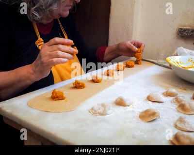 Gros plan sur la fabrication de tortelli farcis avec de la citrouille remplissant des pâtes maison, grand-mère cuisinier de saison 'tortelli di zucca', traditionnel italien rempli pas Banque D'Images