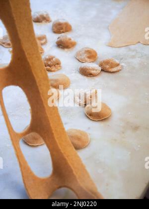 Gros plan sur la fabrication de tortelli farcis avec de la citrouille remplissant des pâtes maison, grand-mère cuisinier de saison 'tortelli di zucca', traditionnel italien rempli pas Banque D'Images