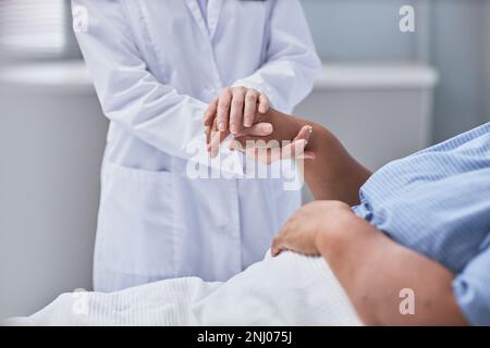 Jeune infirmière soignante tenant les mains d'une patiente dans la chambre d'hôpital, en gros plan Banque D'Images
